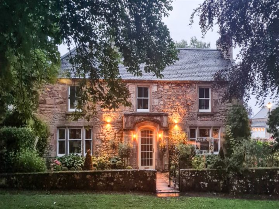 cathedral house hotel at dusk with front lights on and trees in foreground