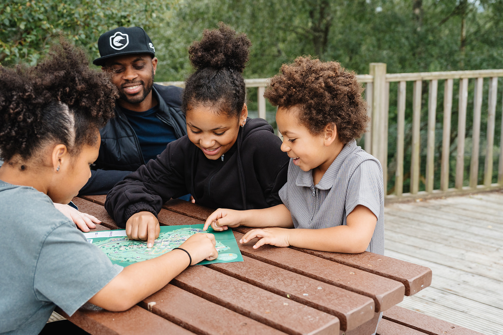 Visitors sitting at a picnic bench looking at a Highland Wildlife Park map. IMAGE: Rachel Hein July 2025